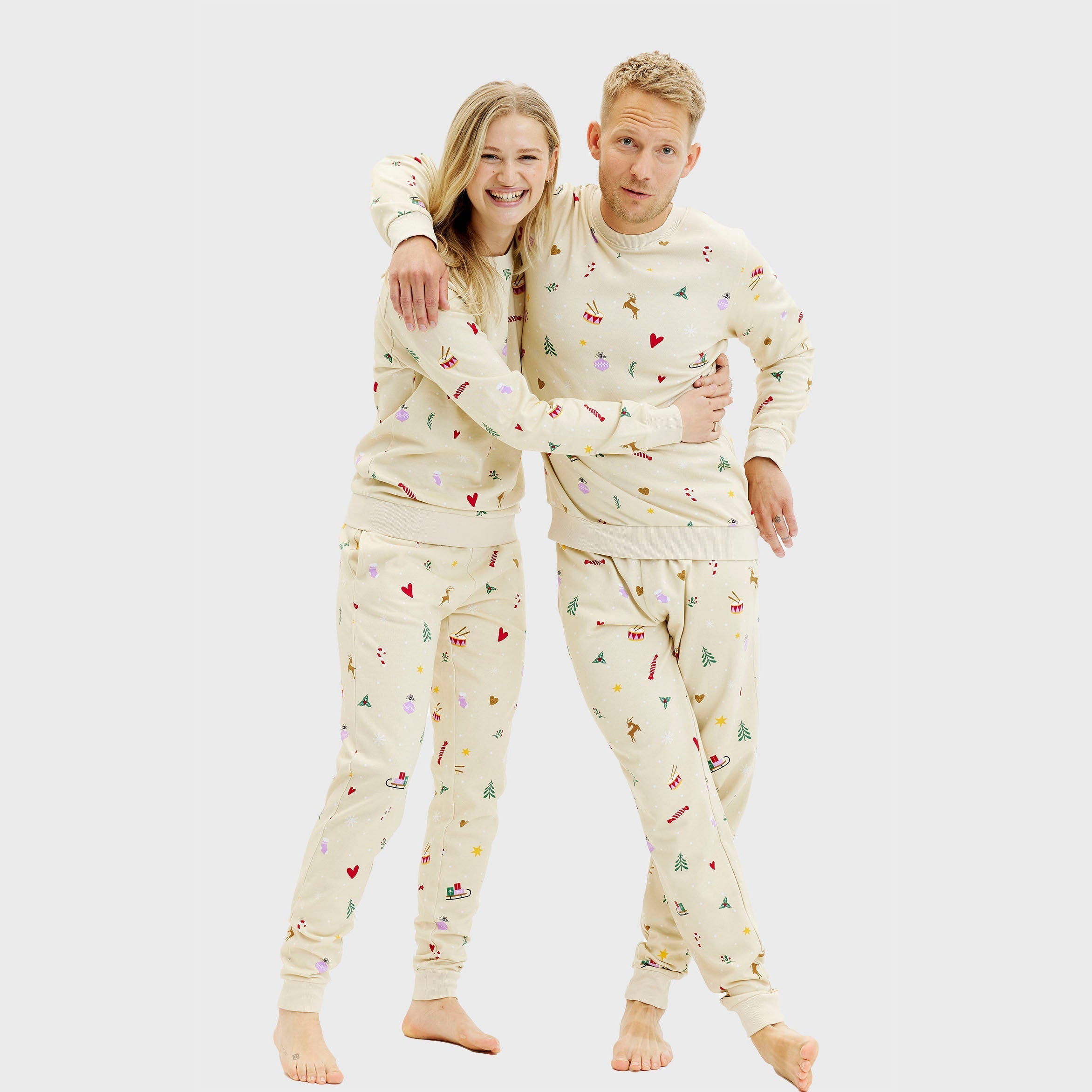 Beiges Weihnachtspyjama Set für Herren und Damen mit festlichem Muster aus Pflanzen und Weihnachtsmotiven.